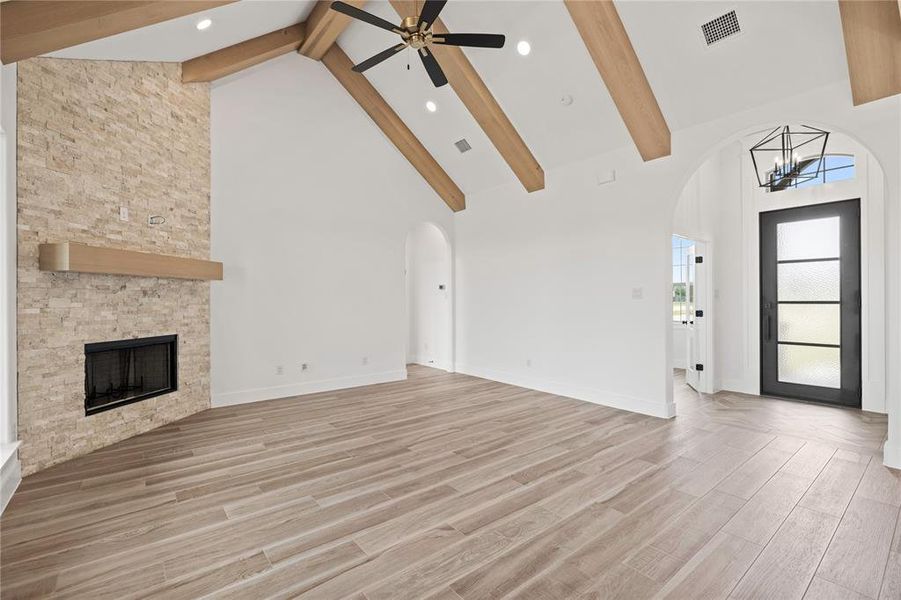 Unfurnished living room featuring high vaulted ceiling, beamed ceiling, a fireplace, light wood-style flooring, and a chandelier Unfurnished living room featuring high vaulted ceiling, beamed ceiling, a fireplace, light wood-style flooring, and a chandelier
