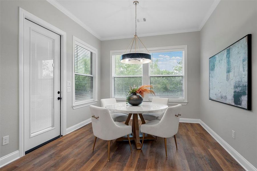 Dining area featuring baseboards, ornamental molding, and dark wood-style floors