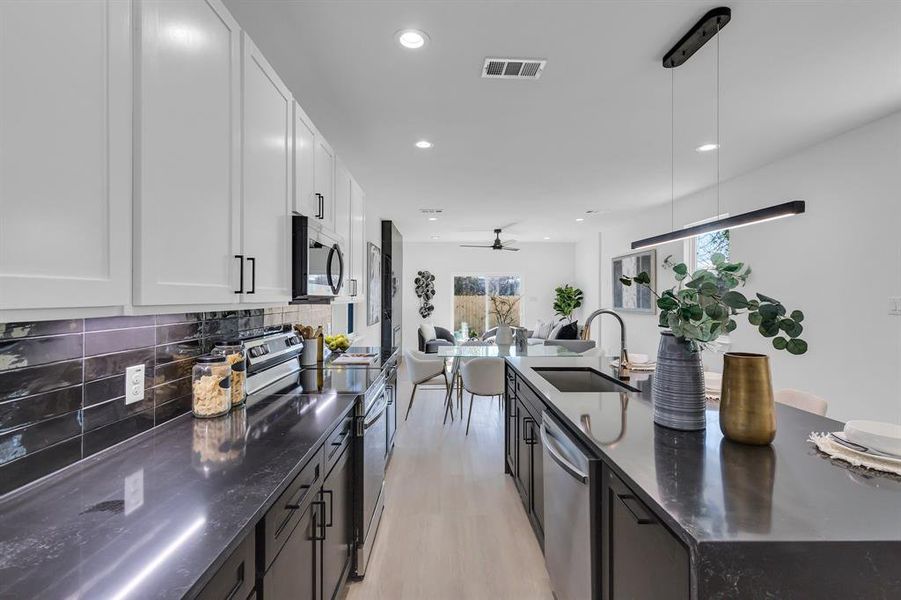 Kitchen with ceiling fan, sink, hanging light fixtures, white cabinets, and appliances with stainless steel finishes