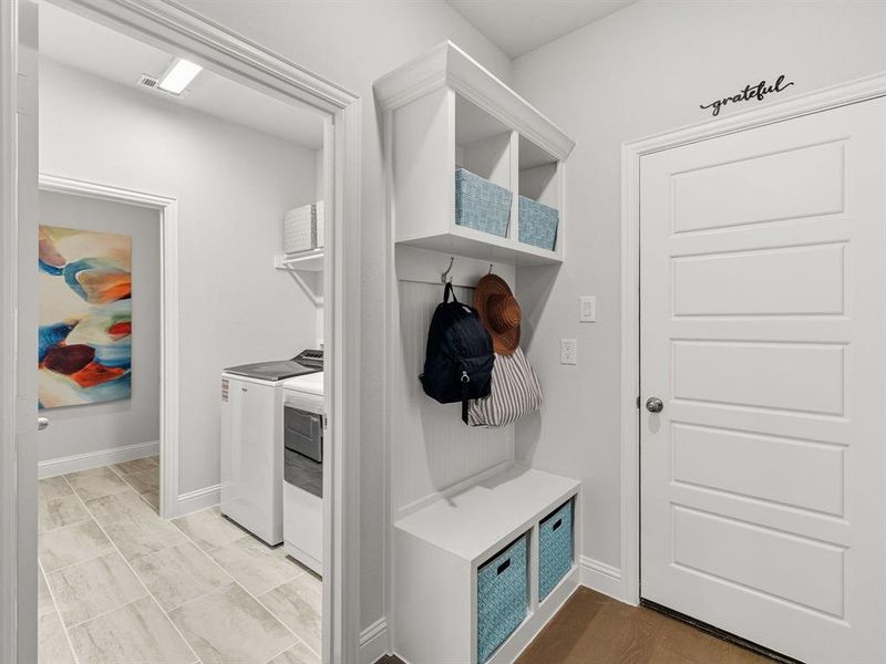 Transition easily from the garage through this functional mudroom space, complete with custom built-in storage hooks and cubbies.