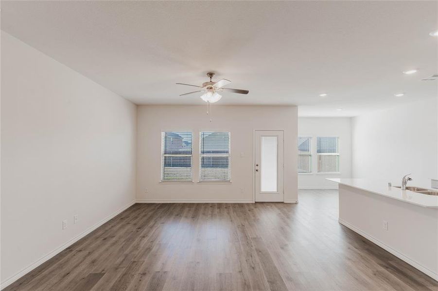 Unfurnished living room featuring dark hardwood / wood-style flooring, sink, and ceiling fan