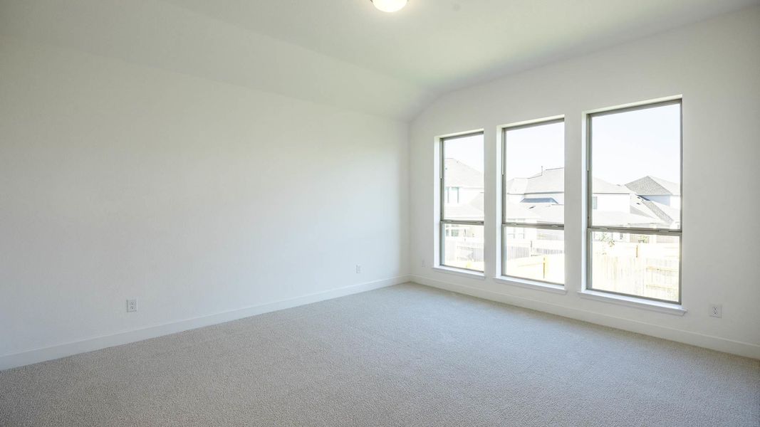 Carpeted empty room with baseboards and vaulted ceiling