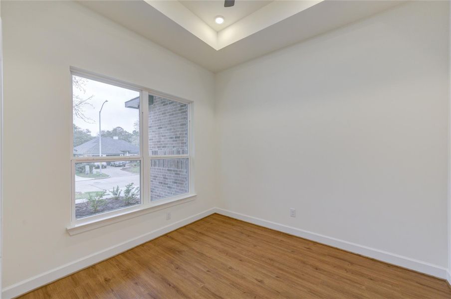 This inviting bedroom features sleek wood flooring, abundant natural light from large windows, and a modern recessed ceiling, offering a cozy and stylish retreat. This inviting bedroom features sleek wood flooring, abundant natural light from large windows, and a modern recessed ceiling, offering a cozy and stylish retreat.