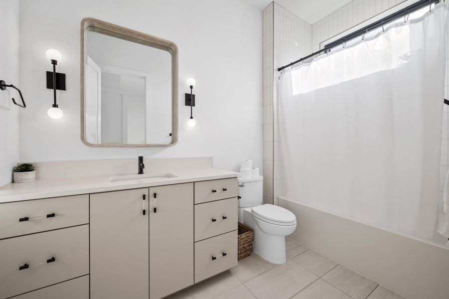 Full bath with toilet, tile patterned flooring, vanity, and shower / bathtub combination with curtain Full bath with toilet, tile patterned flooring, vanity, and shower / bathtub combination with curtain