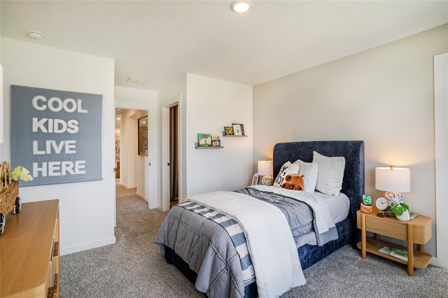 This cozy bedroom features a plush bed with a navy headboard, soft gray carpeting, and warm lighting from bedside lamps. The room has a playful touch with decor and a sign that reads "Cool Kids Live Here." It's perfect for a child's space, offering both comfort and style. This cozy bedroom features a plush bed with a navy headboard, soft gray carpeting, and warm lighting from bedside lamps. The room has a playful touch with decor and a sign that reads "Cool Kids Live Here." It's perfect for a child's space, offering both comfort and style.