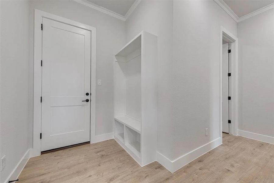 Mudroom with ornamental molding and light wood-style floors