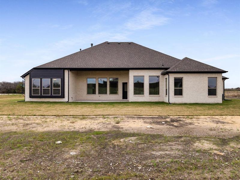Back of house with a lawn, a shingled roof, and a patio
