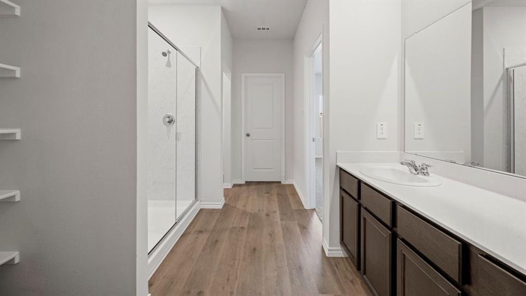 Full bathroom with light wood-style flooring, a marble finish shower, and vanity