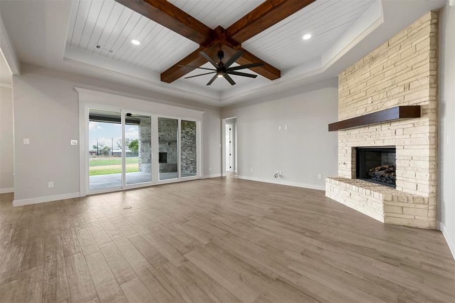 Unfurnished living room with beam ceiling, ceiling fan, wooden ceiling, hardwood / wood-style floors, and a fireplace