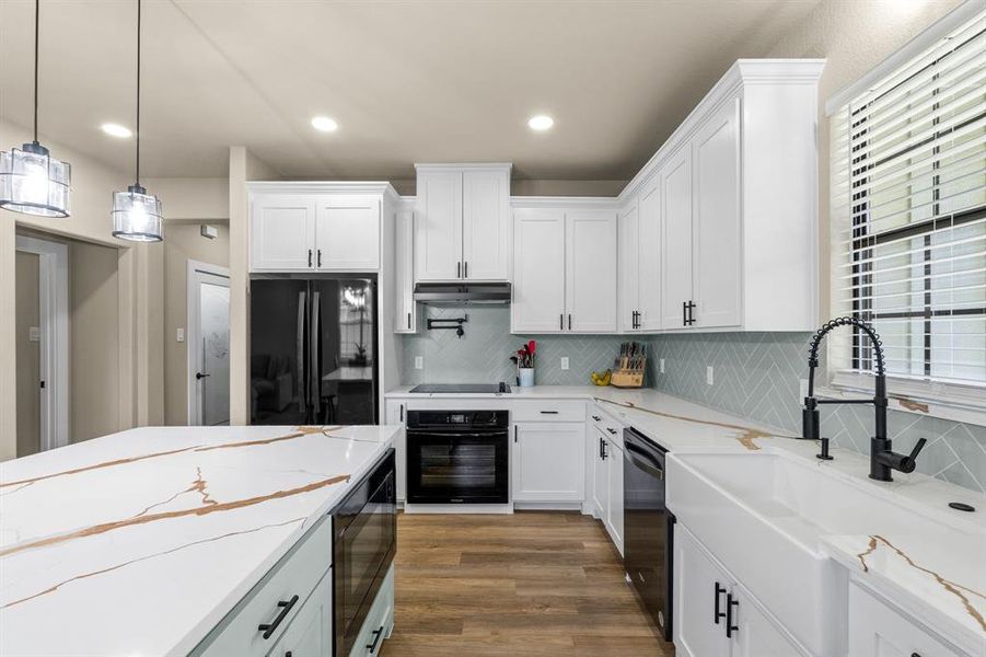 Spacious kitchen featuring an expansive island with quartz countertops and pendant lighting