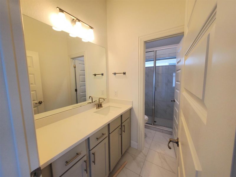 Bathroom with a shower stall, toilet, vanity, and marble finish floor Bathroom with a shower stall, toilet, vanity, and marble finish floor