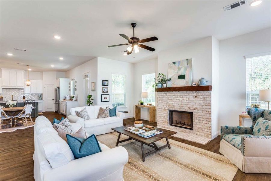 Living room with ceiling fan, a healthy amount of sunlight, dark hardwood / wood-style flooring, and a fireplace