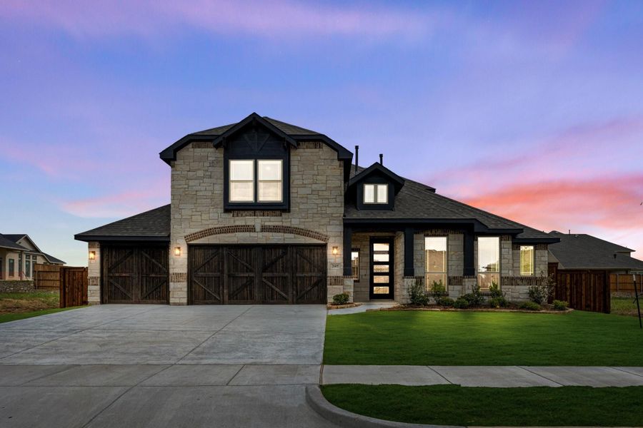 Two-story stone home with dark wood three-car garage, black trim, and manicured front lawn at dusk Two-story stone home with dark wood three-car garage, black trim, and manicured front lawn at dusk