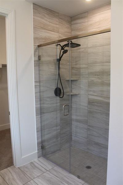 Full bathroom featuring a shower stall and baseboards