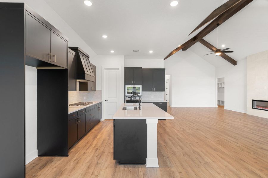 A contemporary kitchen featuring an island with a sink, sleek cabinetry, and integrated appliances, all set against a backdrop of natural wood flooring.
