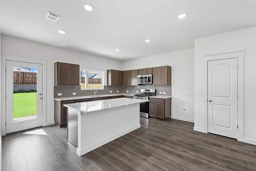 Kitchen with stainless steel appliances, decorative backsplash, dark brown cabinetry, light stone countertops, and recessed lighting Kitchen with stainless steel appliances, decorative backsplash, dark brown cabinetry, light stone countertops, and recessed lighting