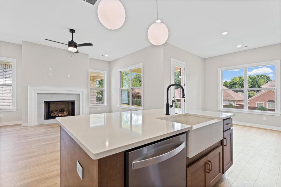 Kitchen island featuring a white countertop, farmhouse sink, and integrated dishwasher Kitchen island featuring a white countertop, farmhouse sink, and integrated dishwasher