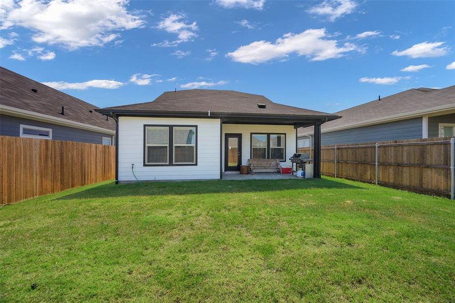 Expansive backyard featuring a manicured lawn and a covered patio Expansive backyard featuring a manicured lawn and a covered patio