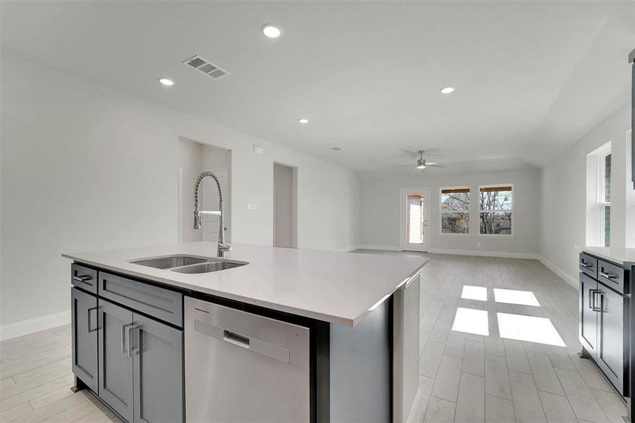 Kitchen with visible vents, dishwasher, open floor plan, light countertops, and a sink