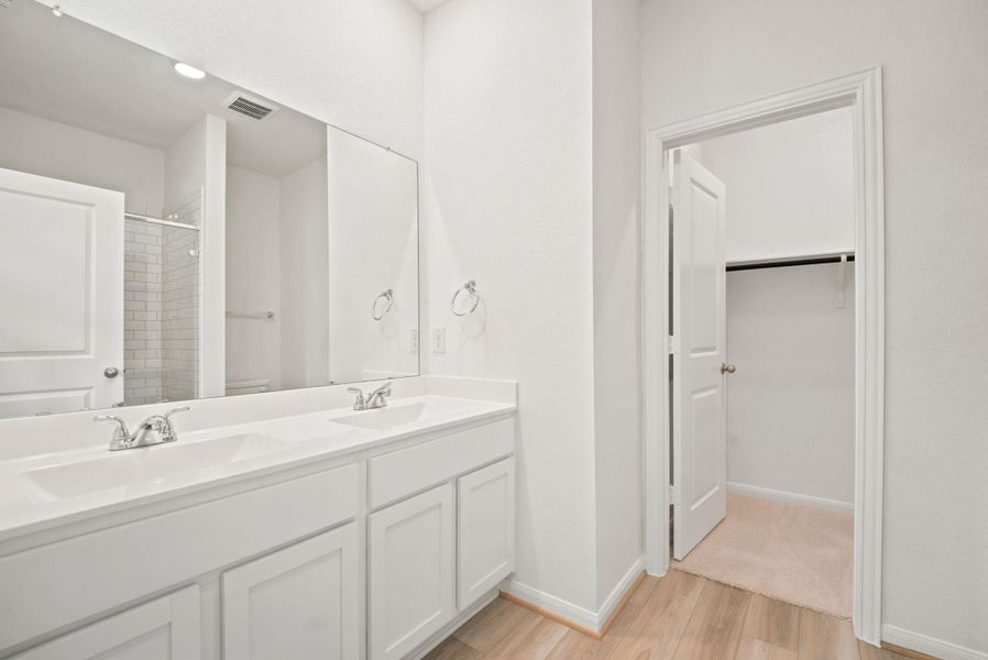 Clean lines and a double vanity highlight this modern bathroom with an adjoining closet.