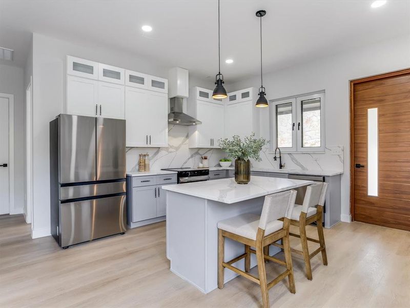 Contemporary kitchen featuring a dual-tone cabinetry design, stainless steel appliances, and wood-finish flooring Contemporary kitchen featuring a dual-tone cabinetry design, stainless steel appliances, and wood-finish flooring
