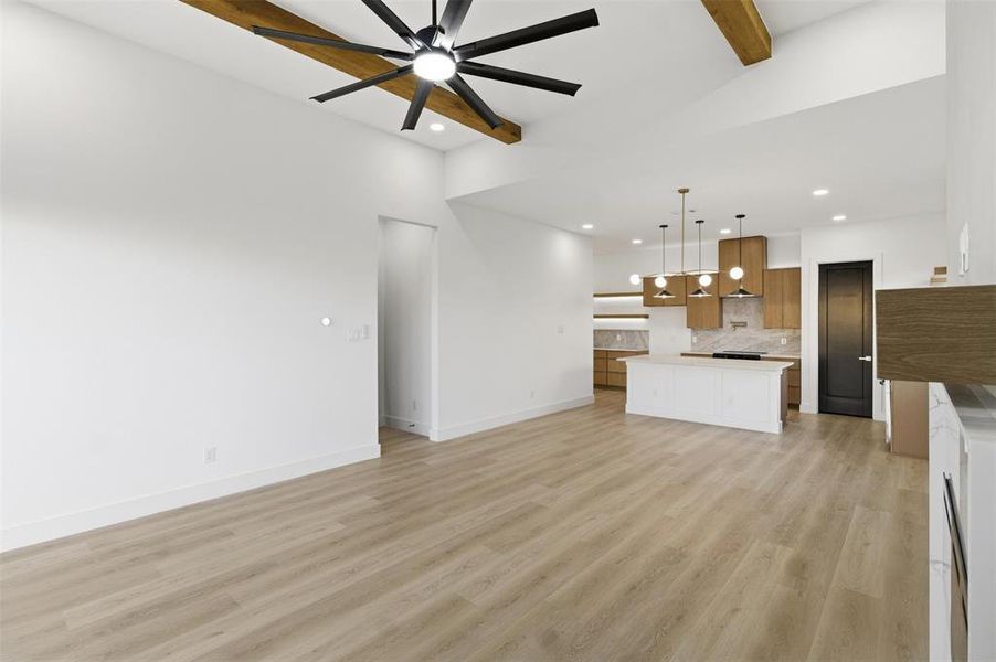 Unfurnished living room with beam ceiling, ceiling fan, light wood-style floors, and recessed lighting