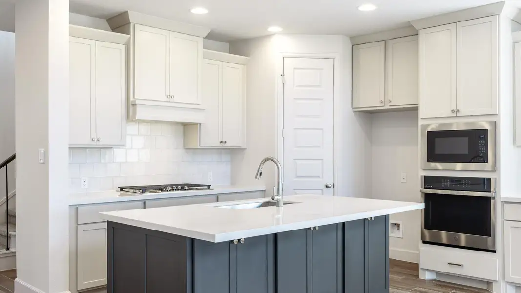 Kitchen featuring stainless steel appliances, dark wood-style floors, decorative backsplash, recessed lighting, and white cabinetry Kitchen featuring stainless steel appliances, dark wood-style floors, decorative backsplash, recessed lighting, and white cabinetry