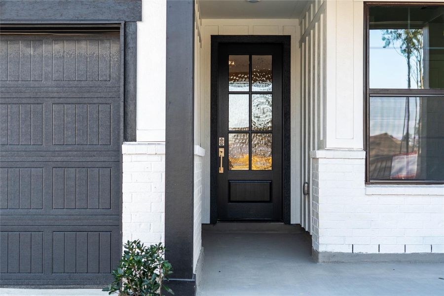 The home's exterior boasts a chic modern farmhouse look, highlighted by a black six-pane entry door with textured glass and a coordinating dark gray horizontal panel garage door. The home's exterior boasts a chic modern farmhouse look, highlighted by a black six-pane entry door with textured glass and a coordinating dark gray horizontal panel garage door.