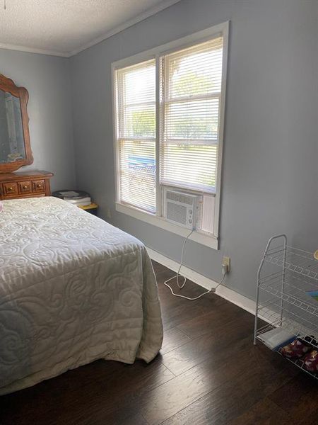 Bedroom with dark hardwood / wood-style floors, ornamental molding, and a textured ceiling Bedroom with dark hardwood / wood-style floors, ornamental molding, and a textured ceiling