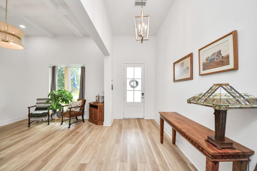 Bright and inviting entryway with high ceilings, leading to an open living area featuring stylish wood flooring and abundant natural light. Bright and inviting entryway with high ceilings, leading to an open living area featuring stylish wood flooring and abundant natural light.