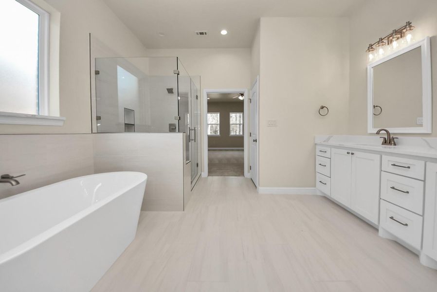 Along with a large glass-enclosed shower, a soaking tub. Neutral tones and natural light create a serene atmosphere.