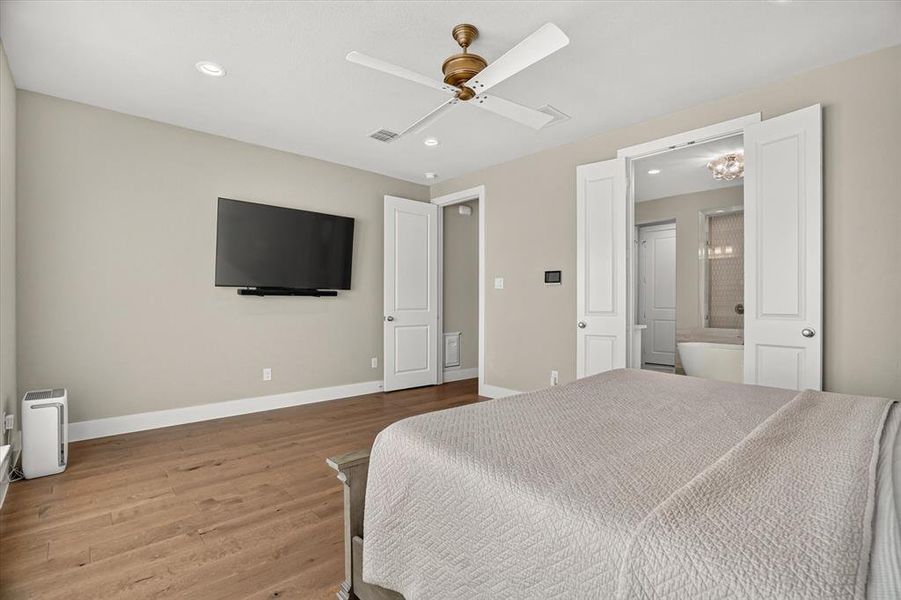 Wood-finish flooring throughout, featuring a ceiling fan with integrated lighting, recessed lighting, and a wall-mounted entertainment system Wood-finish flooring throughout, featuring a ceiling fan with integrated lighting, recessed lighting, and a wall-mounted entertainment system