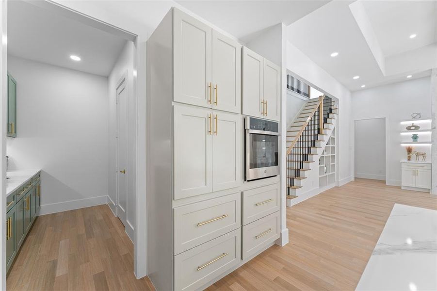 Kitchen featuring light wood-style flooring, recessed lighting, stainless steel oven, and light stone counters