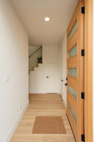 Hall featuring light wood finished floors, stairway, and recessed lighting Hall featuring light wood finished floors, stairway, and recessed lighting