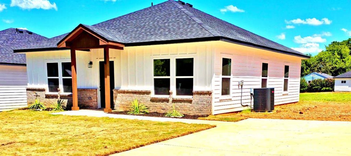 View of front of property featuring a front yard, roof with shingles, covered porch, board and batten siding, and brick siding View of front of property featuring a front yard, roof with shingles, covered porch, board and batten siding, and brick siding