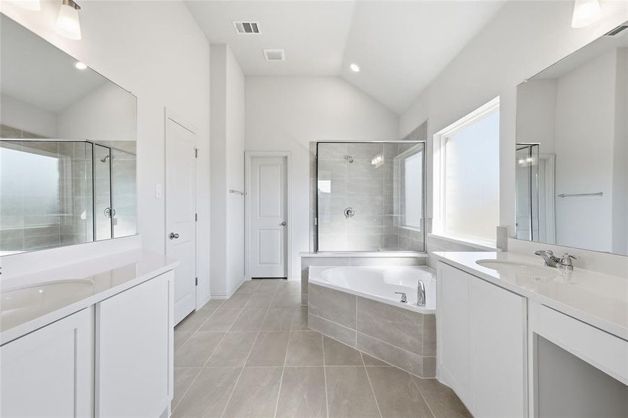 Bathroom with two vanities, a bath, light tile patterned floors, a shower stall, and vaulted ceiling