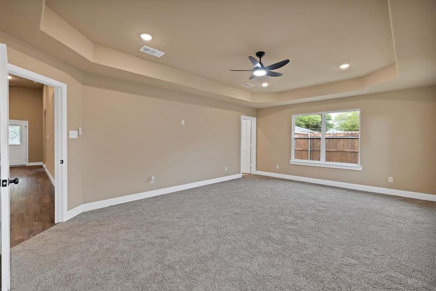 Spare room with carpet, a tray ceiling, visible vents, baseboards, and ceiling fan Spare room with carpet, a tray ceiling, visible vents, baseboards, and ceiling fan