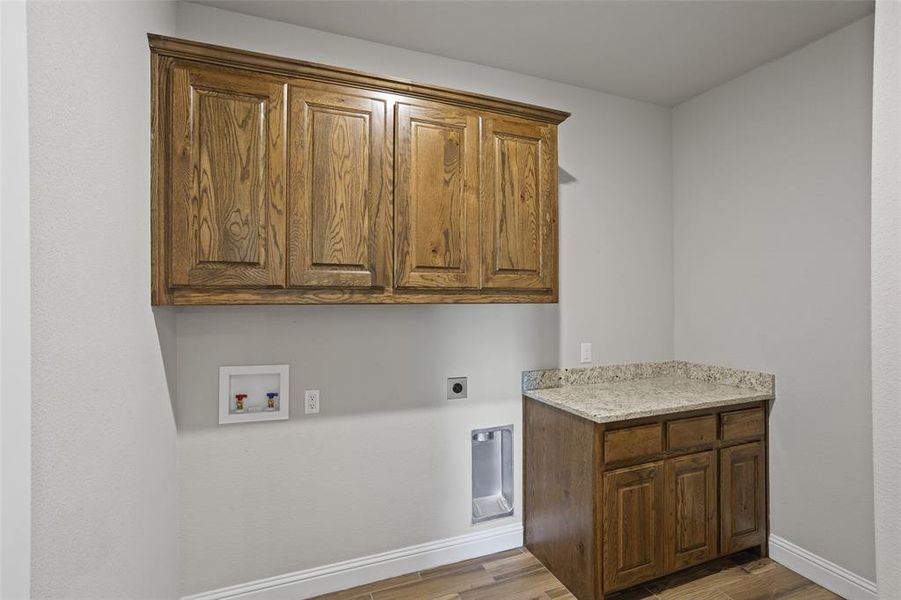 Clothes washing area with washer hookup, electric dryer hookup, cabinets, and wood-type flooring