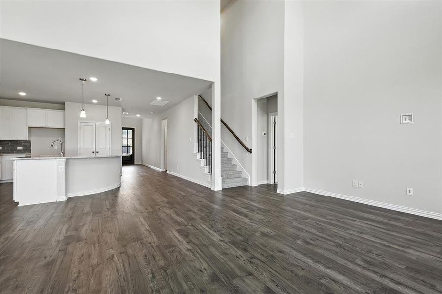 Unfurnished living room featuring dark wood-style flooring, recessed lighting, and a high ceiling