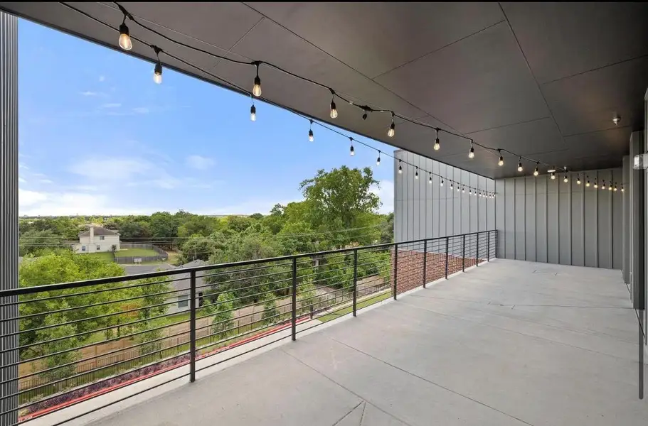 A spacious covered balcony with sleek concrete flooring overlooks surrounding treetops and neighborhoods. A spacious covered balcony with sleek concrete flooring overlooks surrounding treetops and neighborhoods.