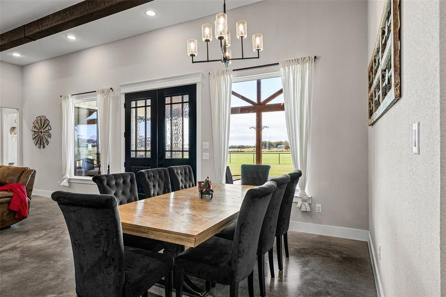 Dining space with concrete flooring, a chandelier, recessed lighting, and beamed ceiling Dining space with concrete flooring, a chandelier, recessed lighting, and beamed ceiling