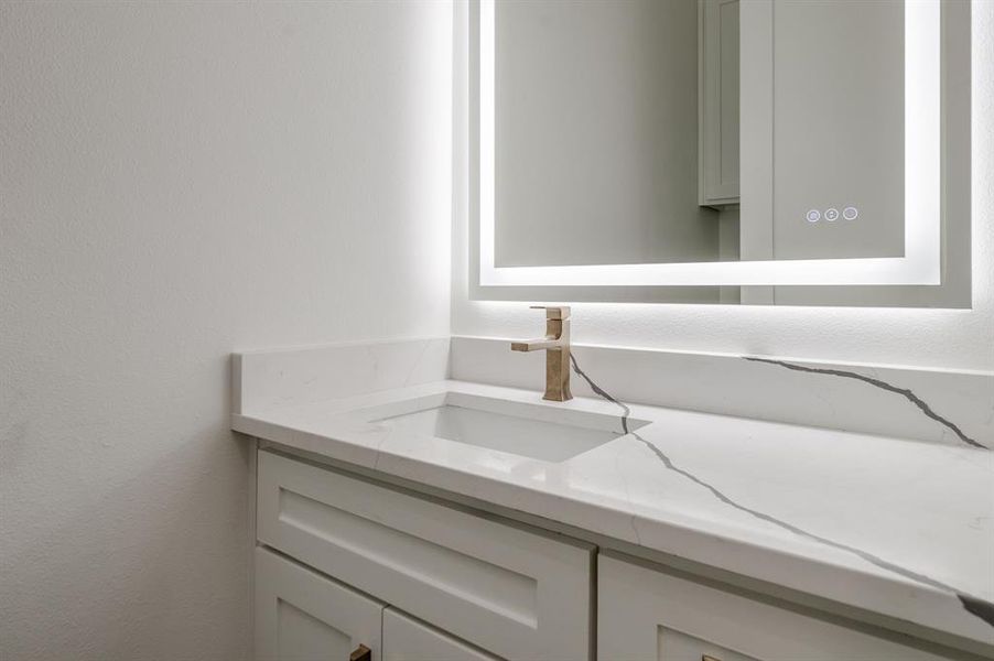 Bathroom featuring vanity and a textured wall Bathroom featuring vanity and a textured wall