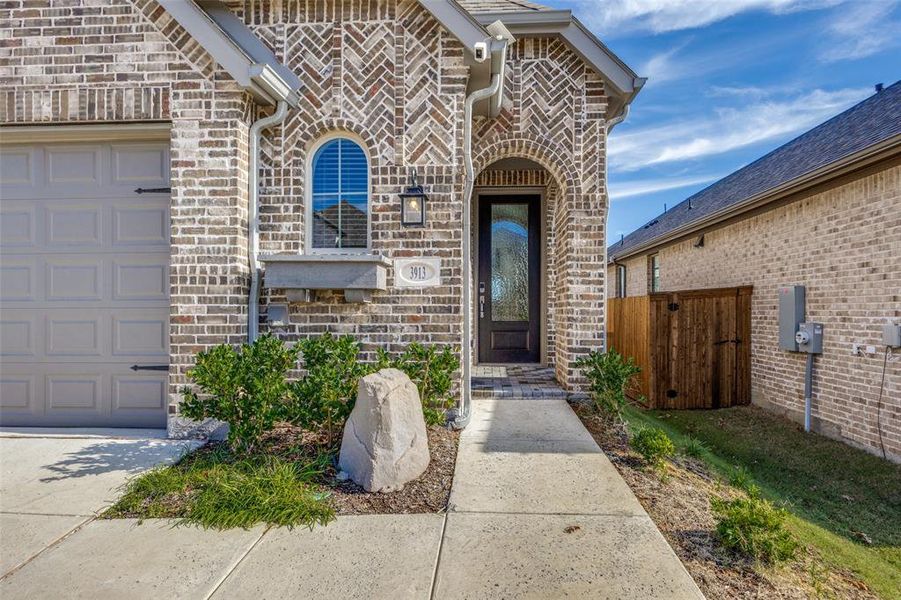 View of exterior entry featuring stone siding, brick siding, and a garage