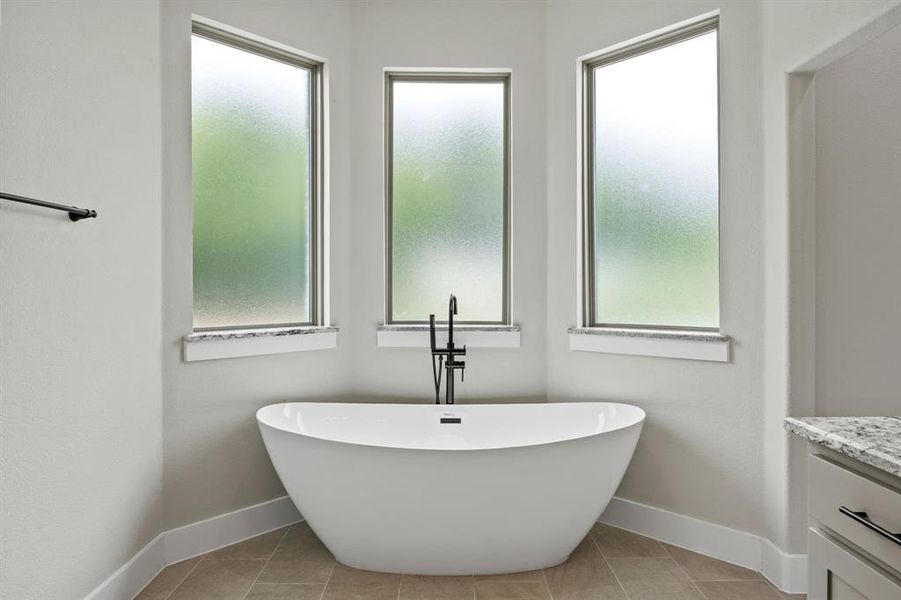 Full bathroom featuring vanity, a freestanding tub, and light tile patterned floors Full bathroom featuring vanity, a freestanding tub, and light tile patterned floors