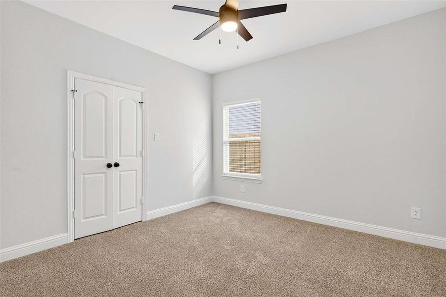 Carpeted spare room with baseboards and a ceiling fan