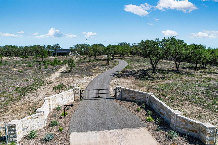 View of asphalt driveway featuring a gate and a view of rural / pastoral area