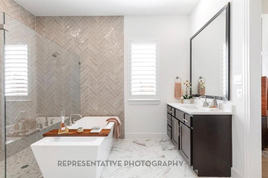 Bathroom with a freestanding bath, vanity, tiled shower, and light marble finish flooring