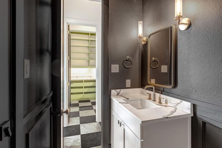 Half bath featuring a textured wall and vanity