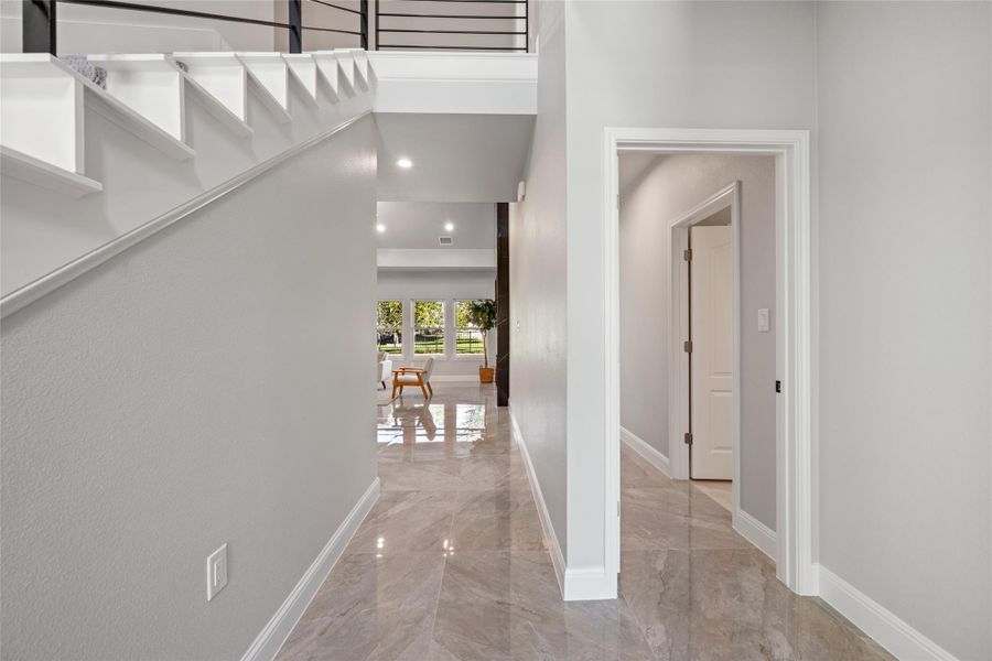 Hallway featuring light marble finish flooring and baseboards