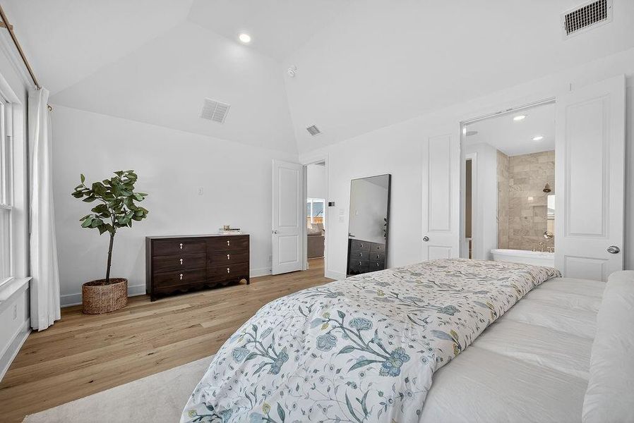 Bedroom with light wood finished floors, recessed lighting, ensuite bath, and high vaulted ceiling Bedroom with light wood finished floors, recessed lighting, ensuite bath, and high vaulted ceiling